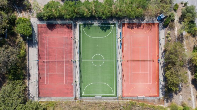Veduta aerea di campi sportivi: due campi da tennis e uno da calcio.