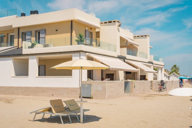 Un edificio moderno sulla spiaggia con ombrelloni e lettini.