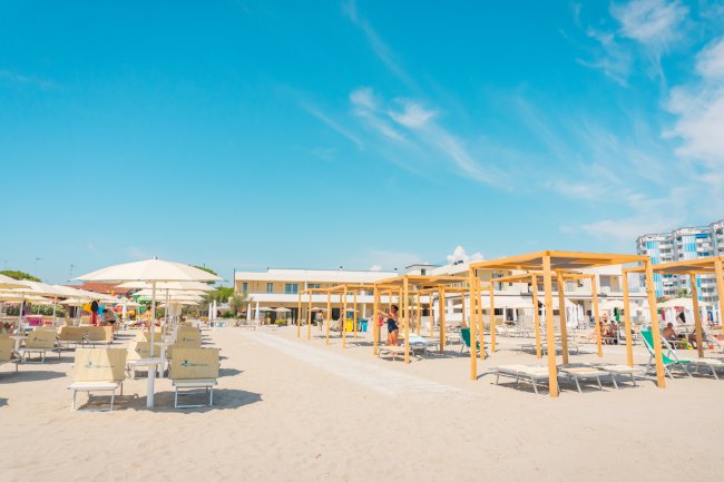 Spiaggia con lettini e ombrelloni sotto un cielo azzurro.