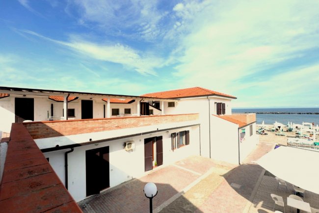 Edificio bianco con tetti rossi vicino a una spiaggia e mare.