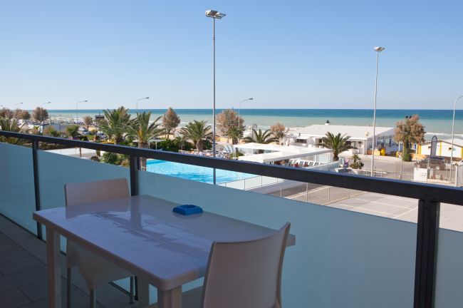 Balcone con tavolo e vista sulla spiaggia e il mare.