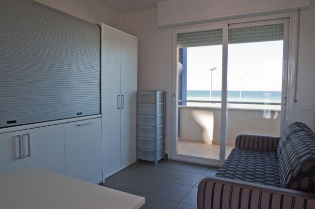 Soggiorno con divano e vista mare da ampie porte finestre.