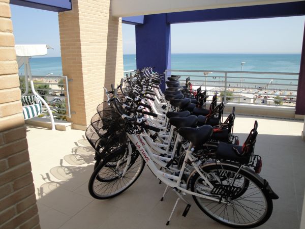 Biciclette allineate su una terrazza con vista sul mare.
