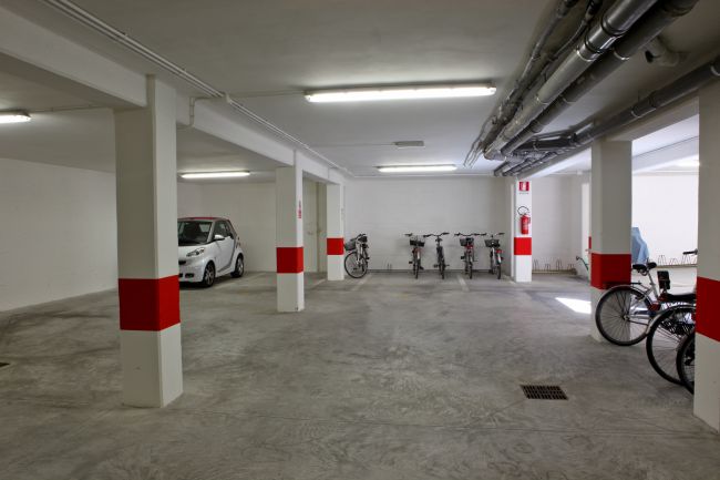 Parcheggio seminterrato con una macchina e varie biciclette.