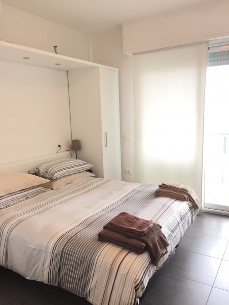Camera da letto moderna con letto matrimoniale, biancheria a righe e asciugamani piegati.