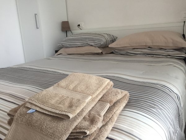 Letto matrimoniale con biancheria a righe e asciugamani beige piegati in primo piano.