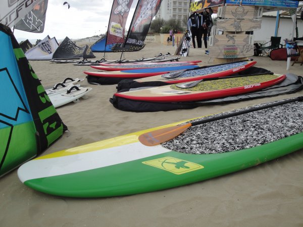 Tavole da surf colorate sulla sabbia con bandiere e tende in spiaggia.
