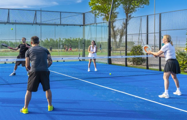 Quattro persone giocano a padel su un campo blu all'aperto.