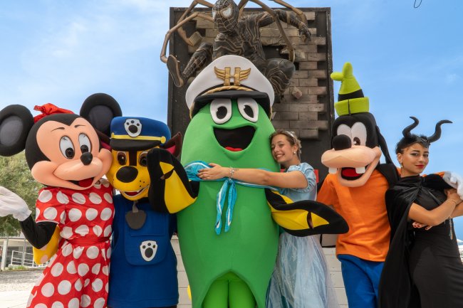 Personaggi in costume, inclusi Minnie e Pippo, posano felici all'aperto.