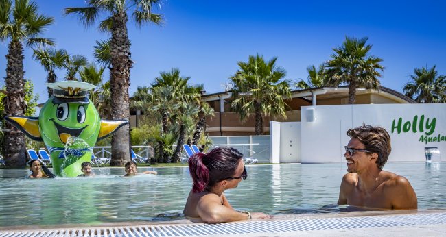 Persone rilassate in una piscina con fontana decorativa a tema marino.
