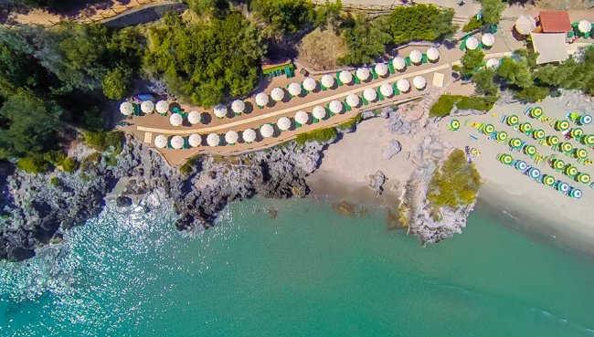 Vista aerea di una spiaggia con ombrelloni e mare turchese.