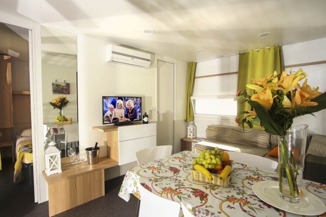 Interno moderno con tavolo apparecchiato, TV e divano.