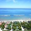 Vista aerea di una spiaggia con mare calmo e case circondate da alberi.
