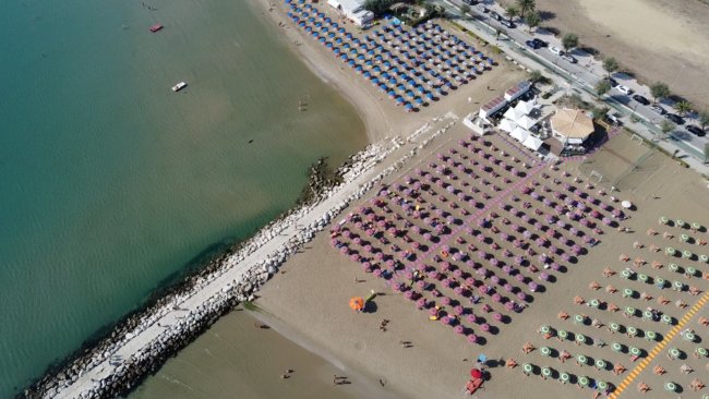 Spiaggia con molti ombrelloni colorati, vista dall'alto. Mare e stabilimenti.