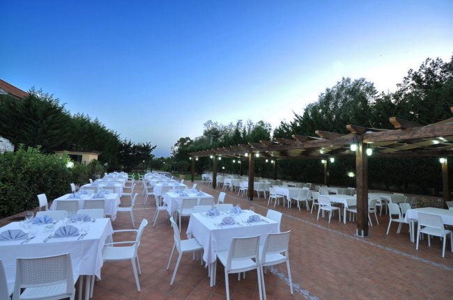 Ristorante all'aperto con tavoli bianchi apparecchiati.