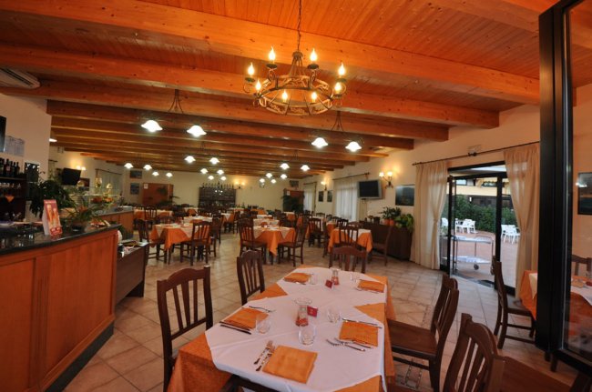 Ristorante con tavoli apparecchiati e soffitto con travi di legno.