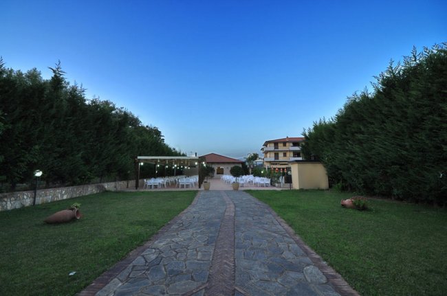 Sentiero di pietra tra siepi e prato.