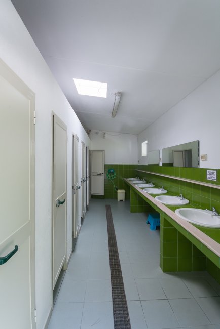 Bagno comune con lavandini e porte verdi.