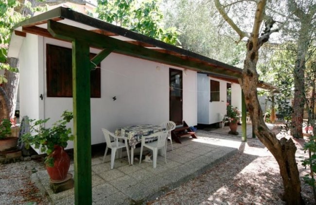 Casa bianca con patio e sedie in giardino.