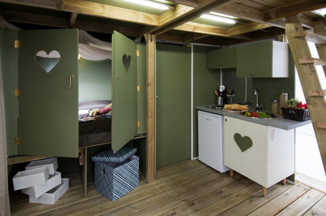 Interno di una capanna con cucina e zona notte.