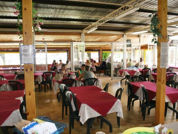 Ristorante con tavoli apparecchiati e sedie di plastica nere.