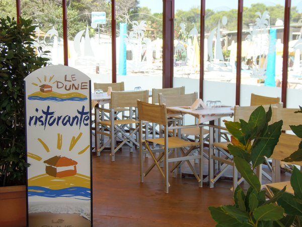 Interno di un ristorante con tavoli apparecchiati e cartello che dice 