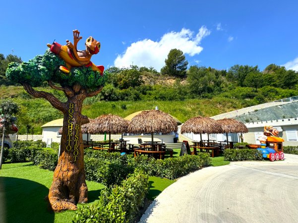 Tavoli con tettoie tropicali e statue di animali.