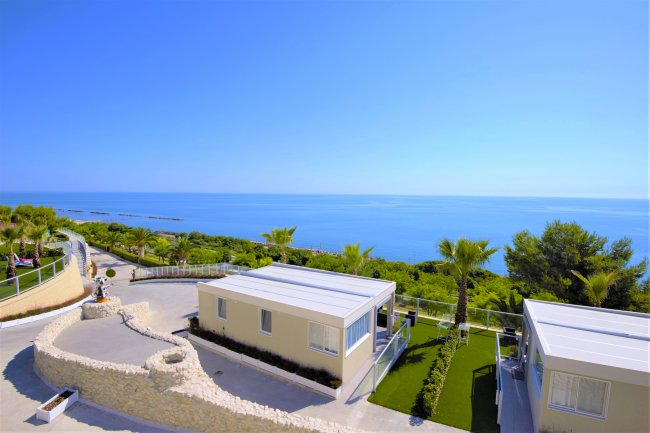 Due case moderne con tetti piatti, vista mare e giardino.