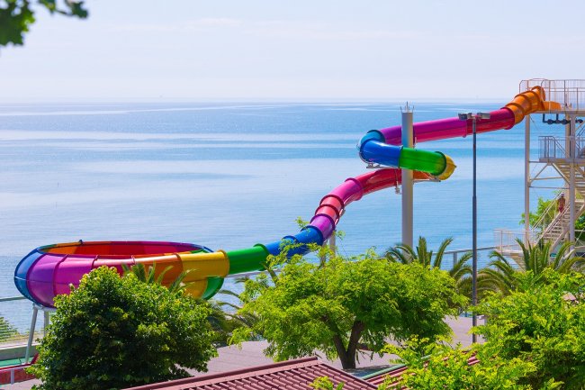 Scivolo d'acqua colorato e curvo che si affaccia sul mare blu.
