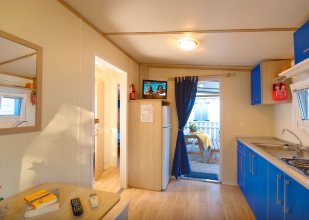 Cucina con frigorifero, ingresso aperto sulla veranda e luci soffuse.