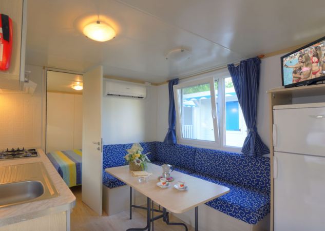 Sala interna con angolo cottura, tavolo e divano blu.