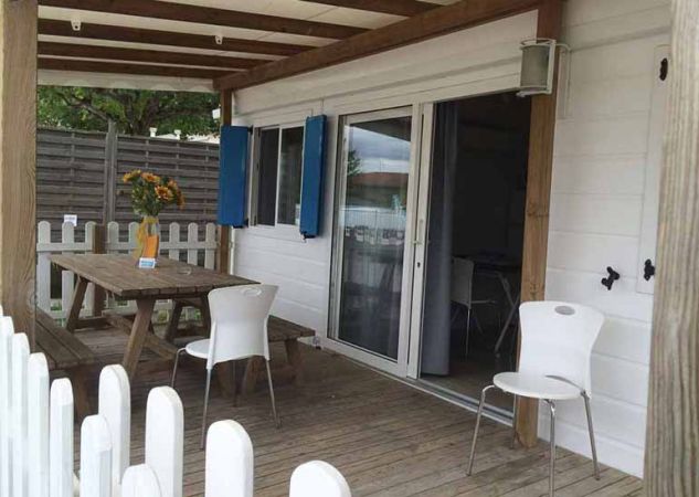 Una veranda con tavolo in legno, sedie bianche e porta scorrevole.