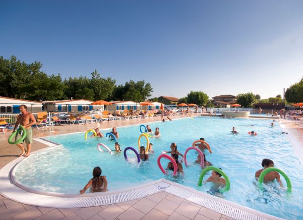 Persone in piscina con ciambelle colorate.