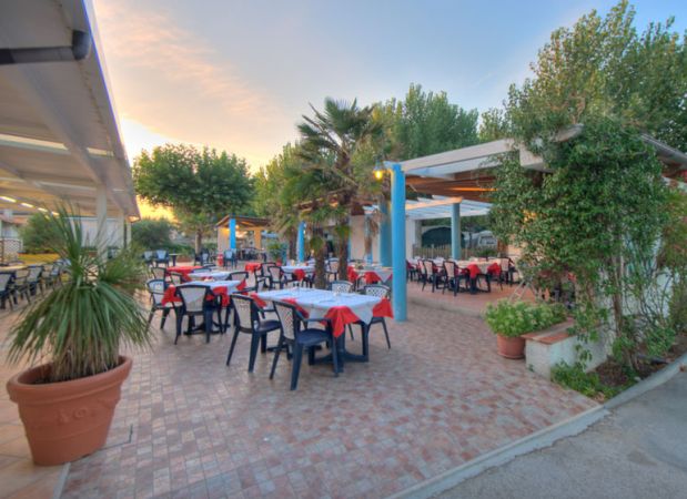 Un ristorante all'aperto con tavoli apparecchiati e sedie sotto pergolati.