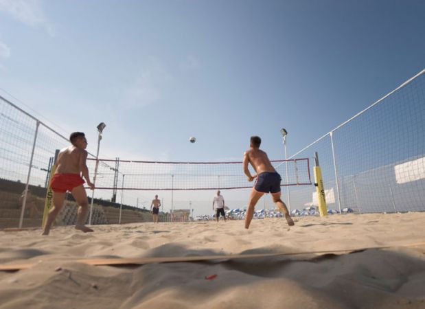 Persone che giocano a beach volley su una spiaggia sabbiosa.