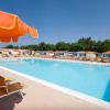 Piscina con lettini e ombrelloni arancioni sotto un cielo blu.