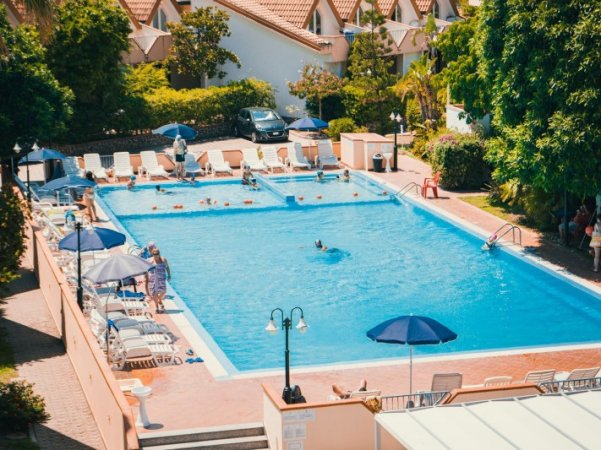 Piscina esterna con lettini e ombrelloni.