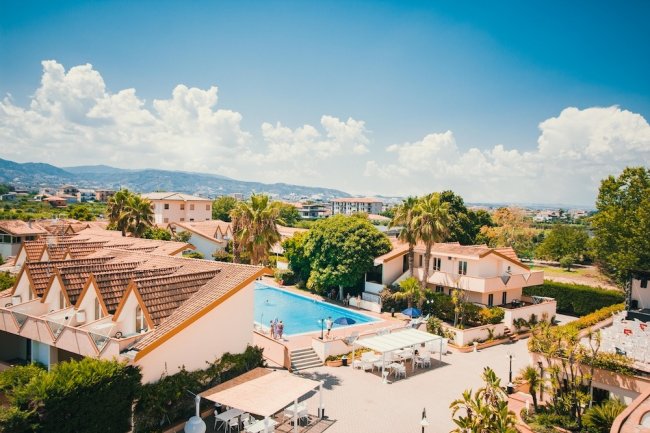 Veduta di un complesso con piscina e tetti rossi.
