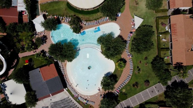 Vista dall'alto di una piscina a forma irregolare con sdraio tutt'intorno.