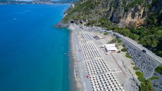 Spiaggia con file di ombrelloni vicino al mare turchese.