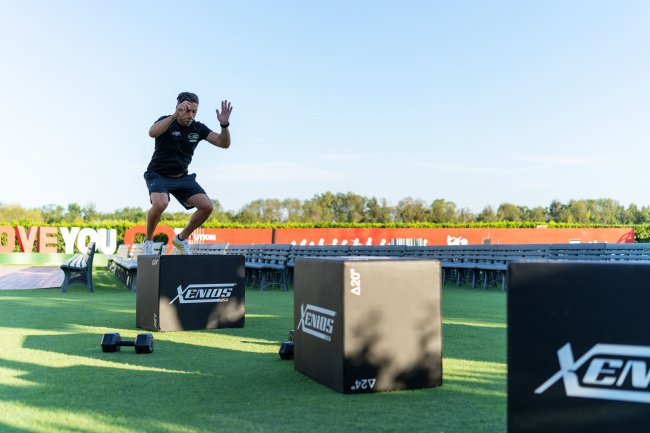 Persona che esegue esercizi di salto su scatole in un campo all'aperto.