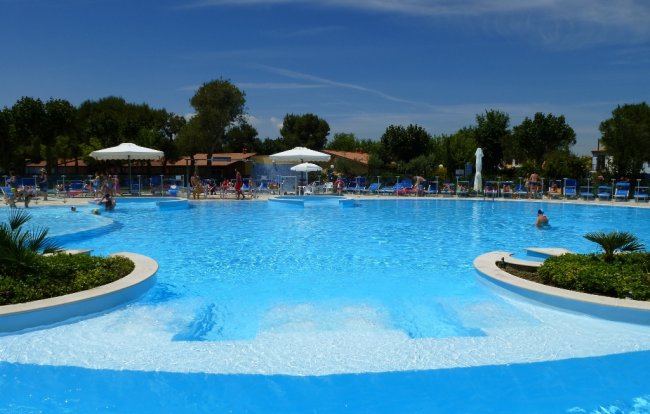 Ampia piscina esterna con isole erbose e bagnanti.