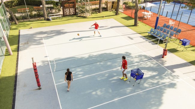 Partita di calcio tennis all'aperto, tre persone giocano su un campo.