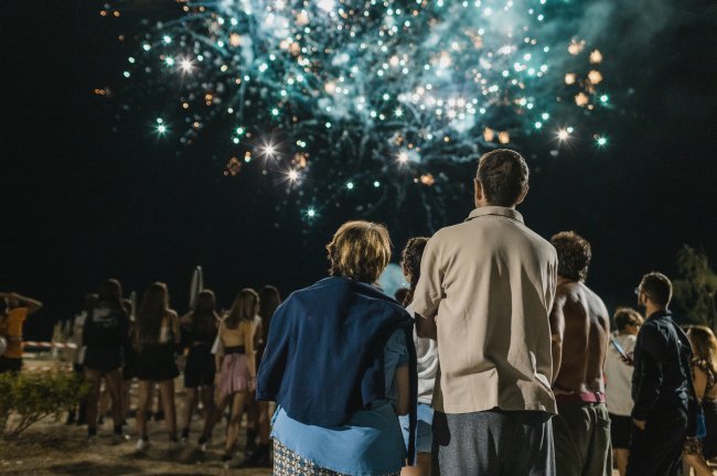 Persone guardano fuochi d'artificio colorati di notte.