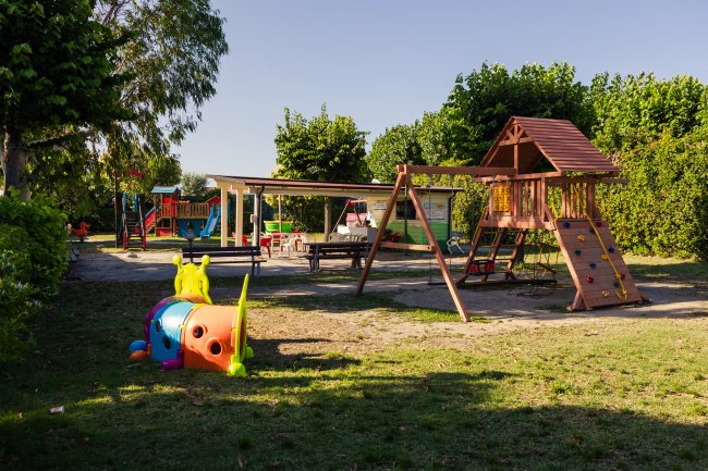 Parco giochi con strutture di legno e un bruco colorato.