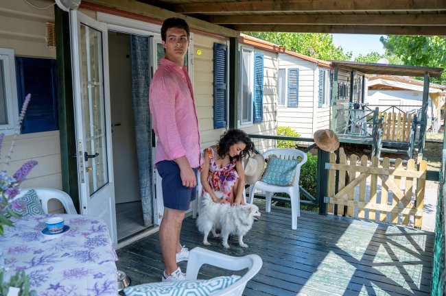 Due persone con un cane su una veranda di casa mobile.