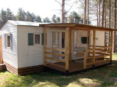 Casa mobile con veranda in legno tra alberi.