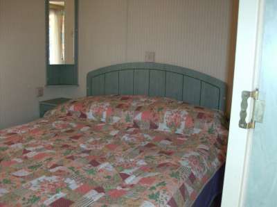 Letto matrimoniale con copriletto decorato a motivi floreali.