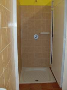 Box doccia piastrellato con mensola per sapone e rubinetto centrale.