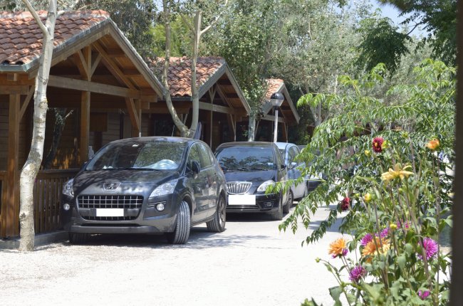 Due auto parcheggiate davanti a bungalow in legno in un'area alberata.